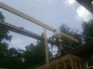 Carpenter setting a ridge beam over a new addition frame — Ice Dam Removal by Roofing Brothers in Constantine