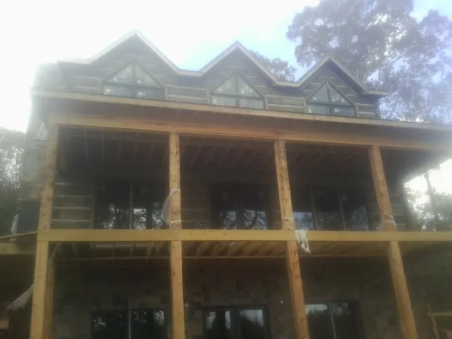 Dormers and porch framing on a large log home under construction — Roof Coating work by our crew in Constantine