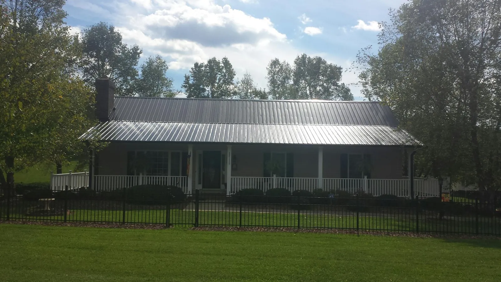 Gray metal roof on a brick ranch with a full width front porch — Gutter Guard Installation work by our crew in Constantine